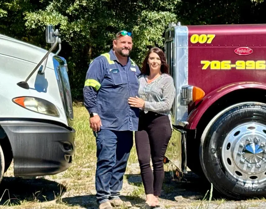 Two people standing between a white truck and a red Peterbilt