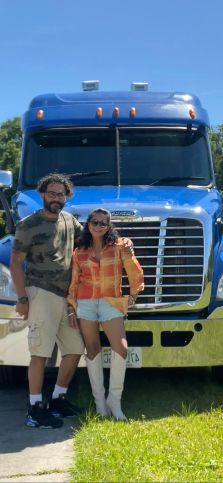 Two people standing in front of a blue Freightliner